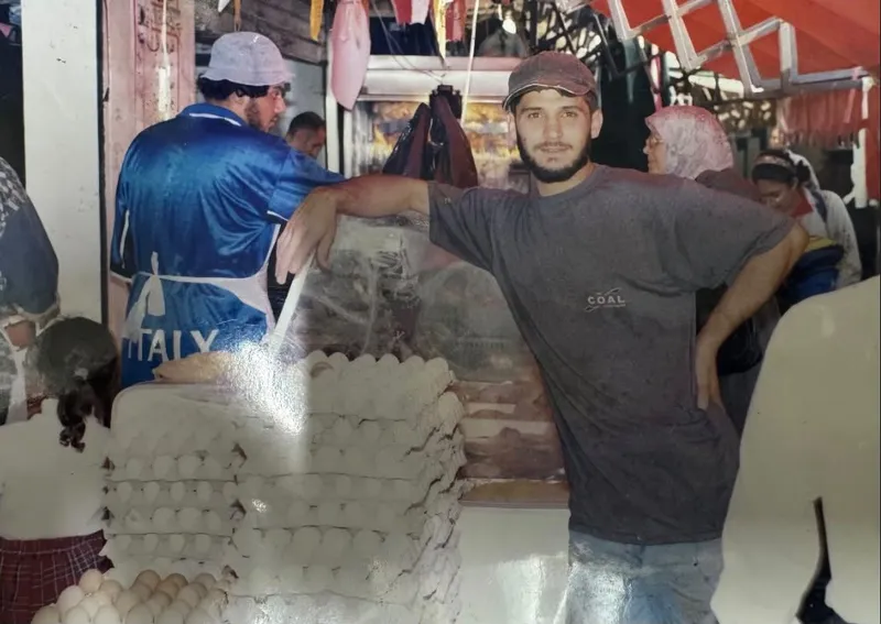 Altes Foto von 1995: Tarek Ismail als junger Mann an einem Marktstand in Beirut, vor gestapelten Eierkartons